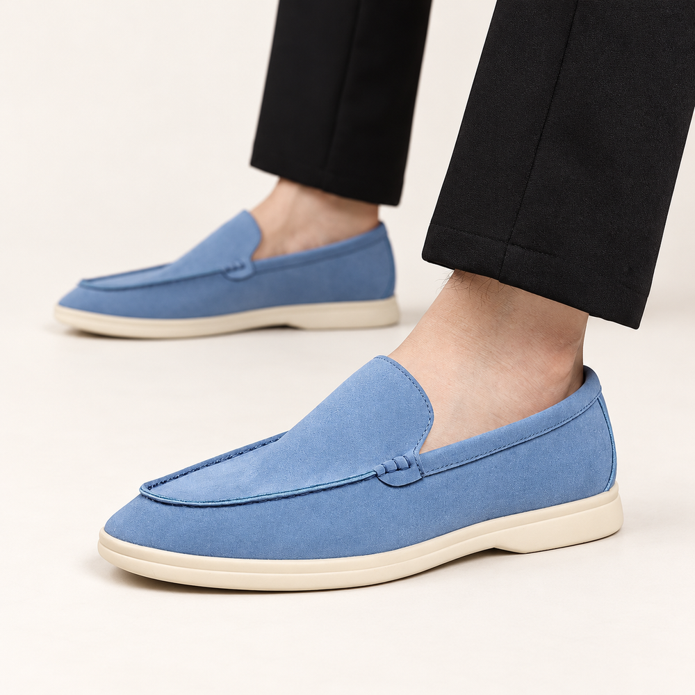 Sky Blue Windsor Suede Loafers worn with black trousers, standing naturally on an ivory studio floor